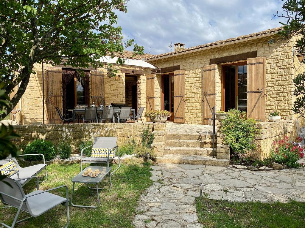 une maison en pierre avec des chaises et une table dans la cour dans l'établissement Maison provençale sur la colline, à Caumont-sur-Durance