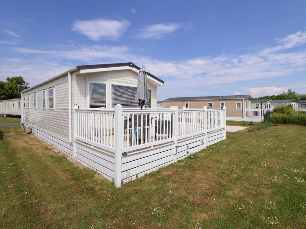 a white mobile home with a white fence at Lawi39 in Abergele