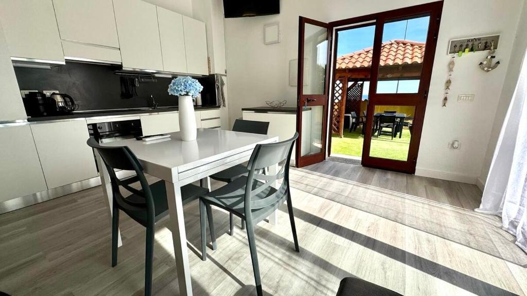 una cocina con mesa y sillas blancas en Blu Caletta - waterfront apartment with garden, en La Caletta