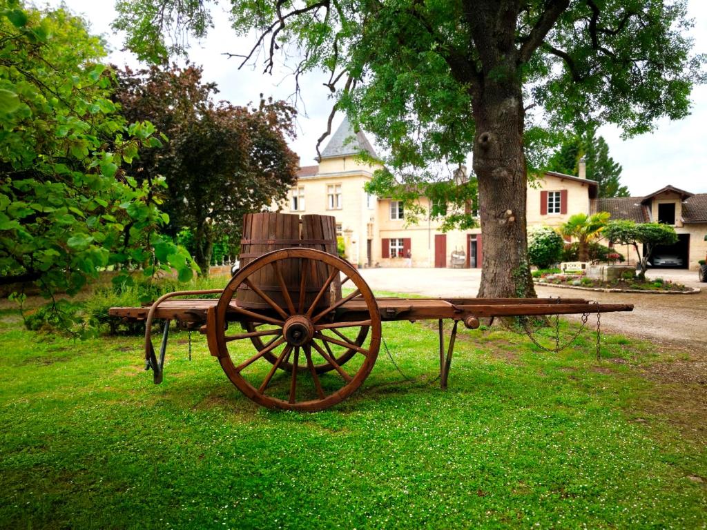 une charrette en bois assise dans l'herbe à côté d'un arbre dans l'établissement Chateau La Croix De Millorit, à La Reuille