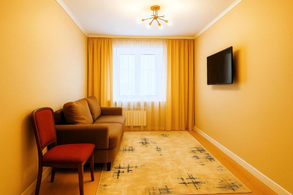 a living room with a chair and a couch and a window at Уютная квартира с видом на лес рядом с Боровым и Rixos in Shchūchīnsk
