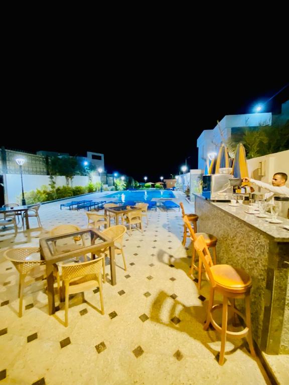a group of tables and chairs next to a swimming pool at night at Tiba Rose hurghada in Hurghada