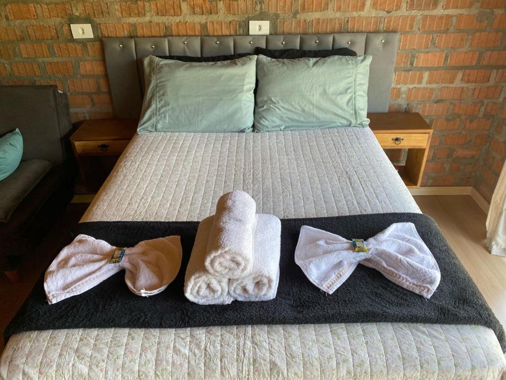a bed with two towels and two robes on it at Pousada Refúgio das Águas Quarto 2 in Chapecó