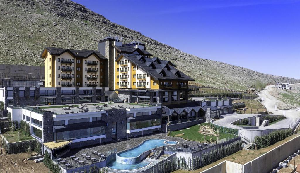 a building with a swimming pool in front of a mountain at Radisson Blu Resort & Spa, Korek Mountain in Rawandoz