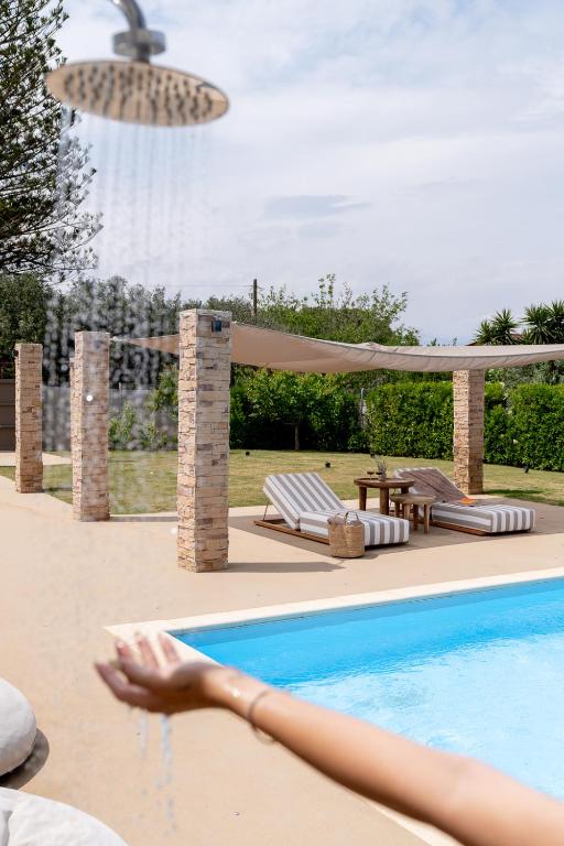 a person laying on the edge of a swimming pool at Villa Hyacinth by A&D Properties in Porto Rafti