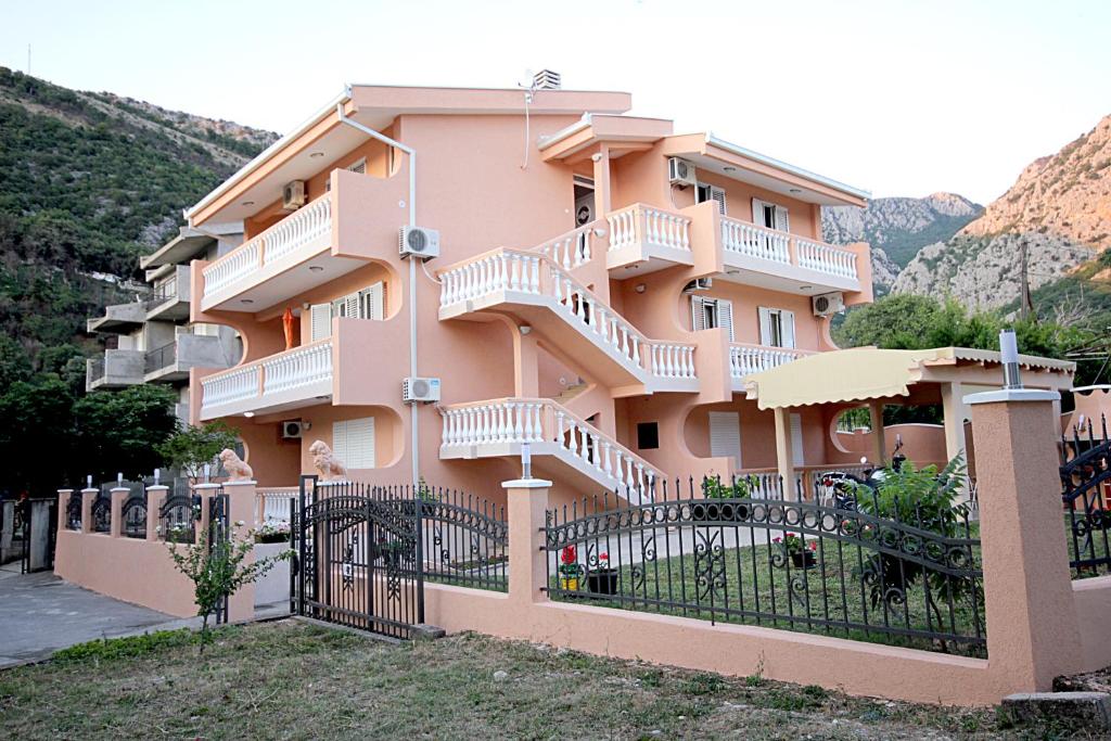 un edificio rosa con escaleras en el lateral en Apartmani Milacic, en Sutomore