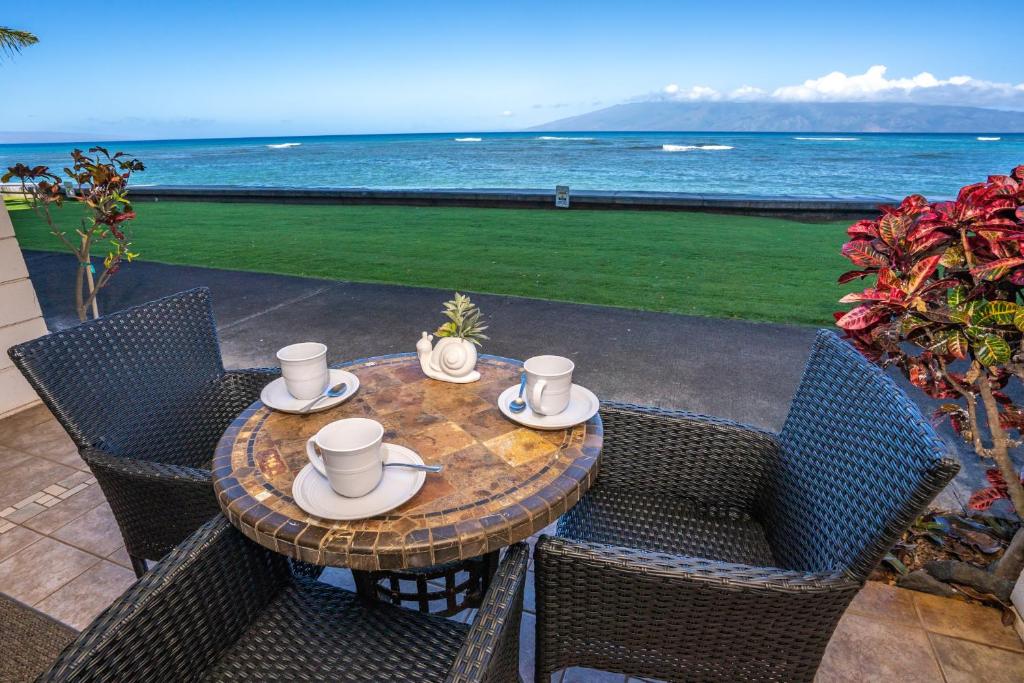 a table with four chairs and a table with a view of the ocean at Kahana Reef 120 by Coldwell Banker Island Vacations in Kahana