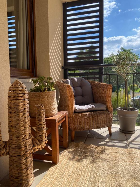 - une terrasse couverte avec des chaises en osier, une table et une fenêtre dans l'établissement Séjour Evasion à Uzès, à Uzès