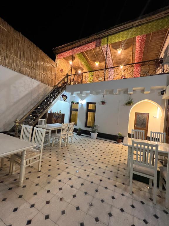 una habitación con mesas y sillas y una escalera en Zardozon Guest House, en Bukhara