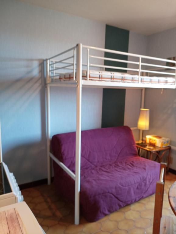 - une chambre avec des lits superposés et un canapé violet dans l'établissement studio à 50 m de la plage , idéal pour 2, avec parking 2NOUMÉA35, à Canet