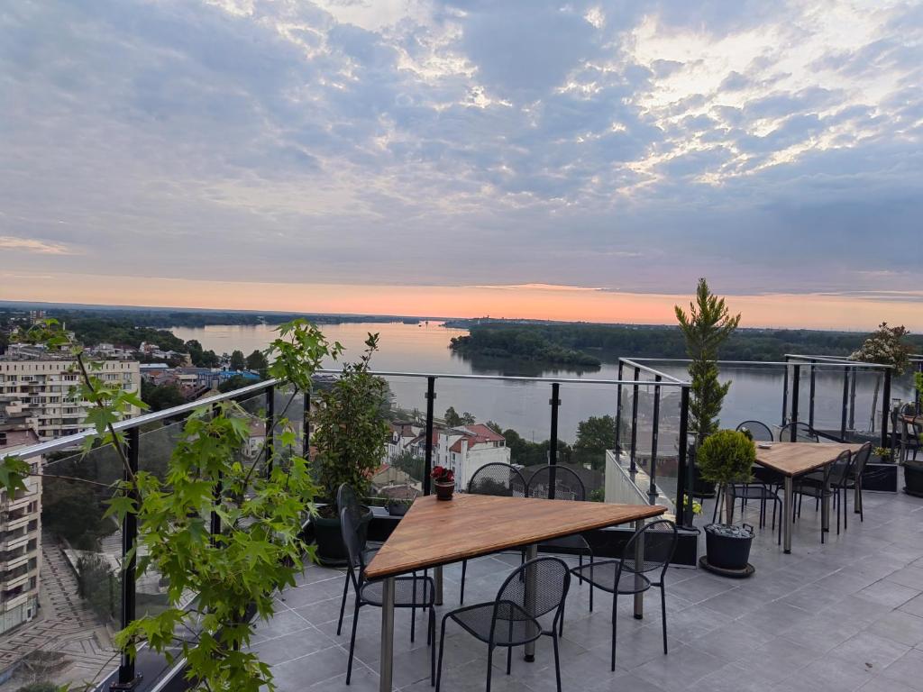a balcony with tables and chairs and a view of a river at Rovno Hotel in Vidin