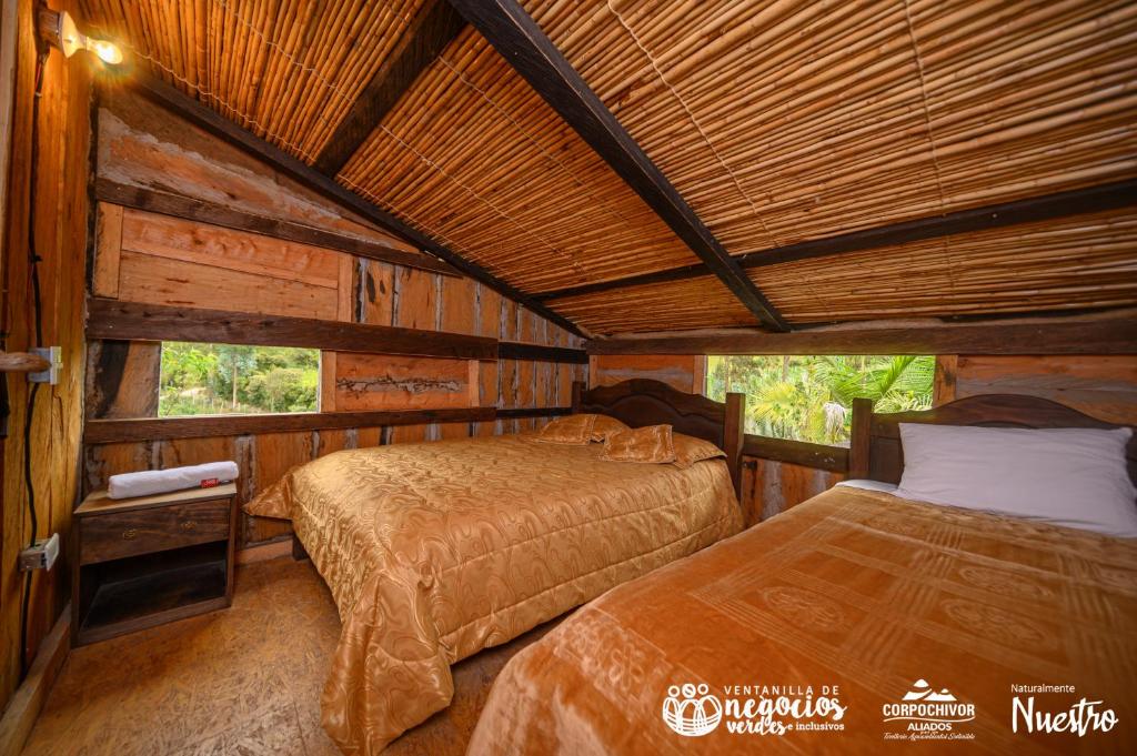 a bedroom with two beds in a cabin at Hospedaje rural Casa del Viejo in Tibaná