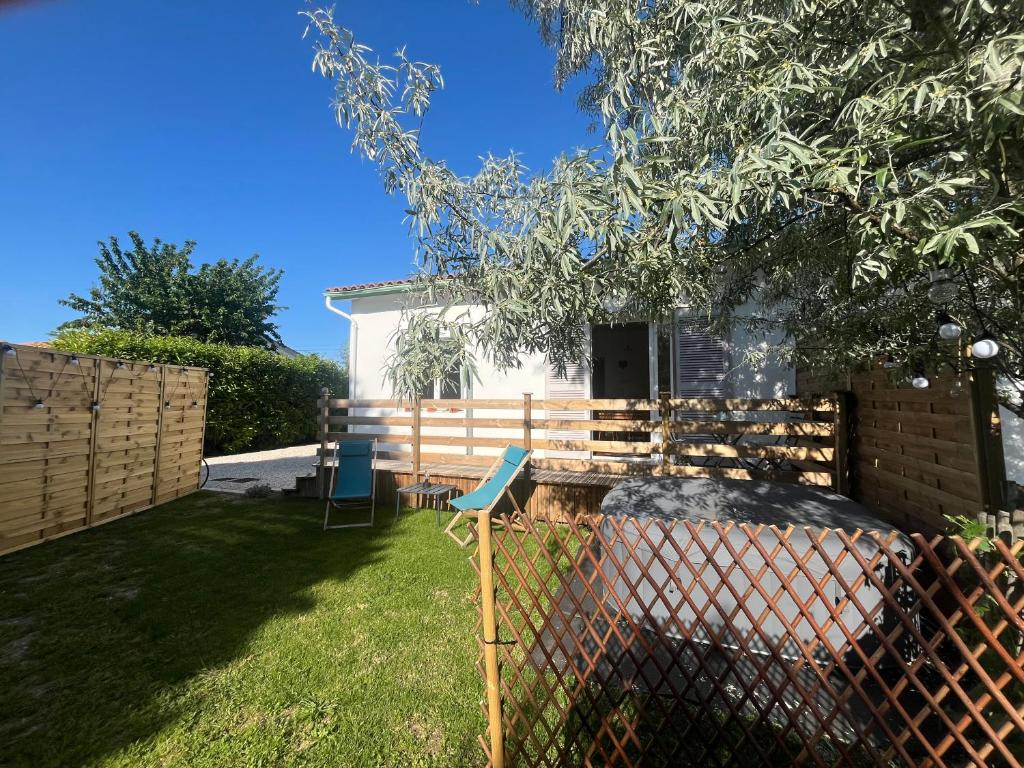 une cour avec une clôture, une table et des chaises dans l'établissement Appartement avec jardin et SPA proche centre-ville et plage, au Château-dʼOléron