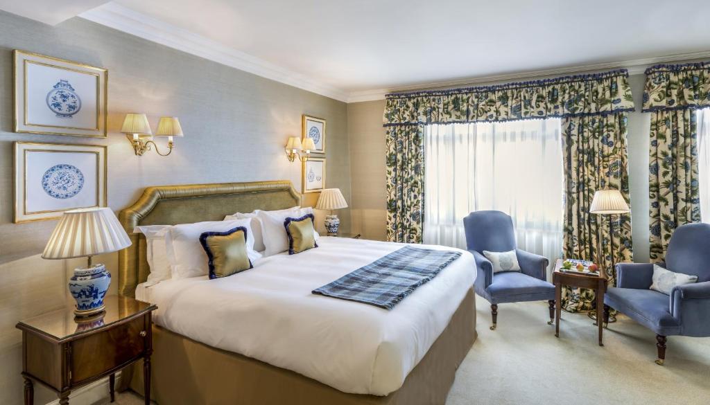 ein Hotelzimmer mit einem großen Bett und zwei Stühlen in der Unterkunft The Stafford London in London