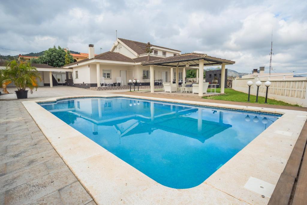 a swimming pool in front of a house at Holiday Villa Benmar in Castellón de la Plana