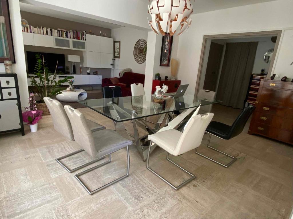 une salle à manger avec une table en verre et des chaises blanches dans l'établissement Chez Violette, à Avignon