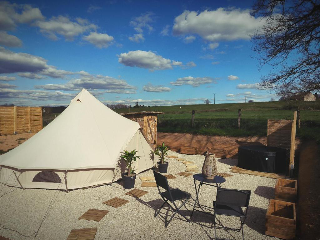 une tente blanche avec des chaises et une table dans l'établissement Tente lodge avec Jacuzzi privatif, à Lapalisse