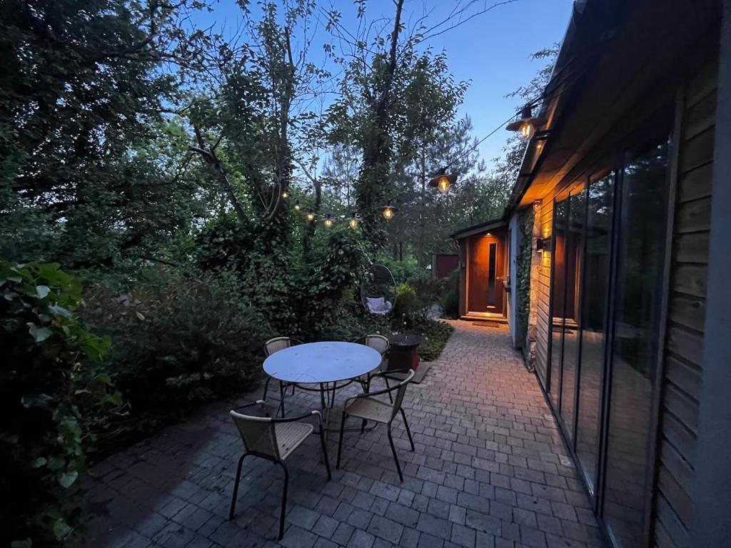 eine Terrasse mit einem Tisch und Stühlen auf einer Backsteinterrasse in der Unterkunft Beili Glas Cottage in Pontardawe