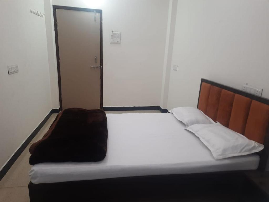 a bedroom with a white bed with a wooden headboard at annpurna home stay in Ujjain