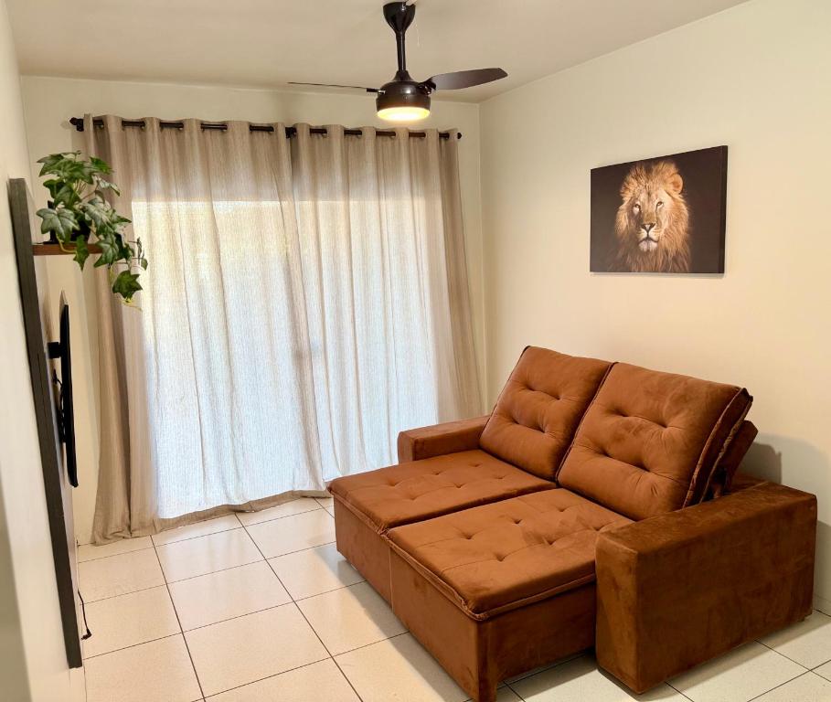 ein Wohnzimmer mit einem braunen Sofa vor einem Fenster in der Unterkunft Ap Conforto no Centro de Sinop in Sinop