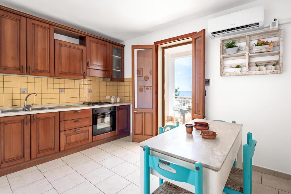 a kitchen with wooden cabinets and a table and a window at Terrazza fronte Mare in Castro di Lecce