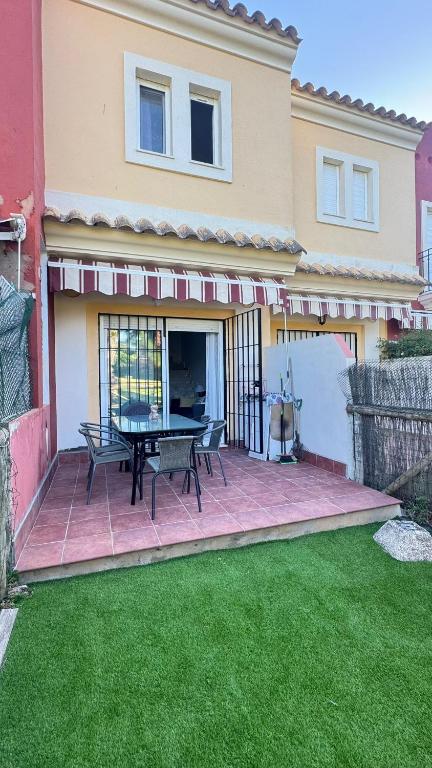 a patio with a table and chairs in front of a house at Adosado Cigüeñas IV-Islantilla Golf in Huelva