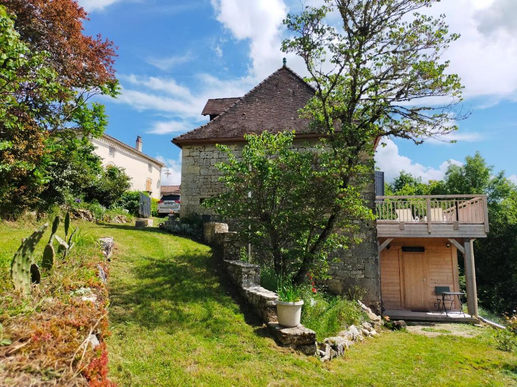 an old stone house with a balcony and a yard at Au Coeur du Lot - Entre Cahors et Rocamadour in Bellefont-La Rauze