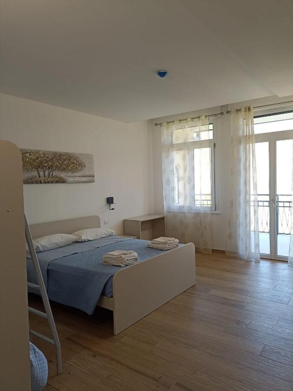 a white bedroom with a bed and a large window at Edera Hall Inclusive in Cerano d'Intelvi