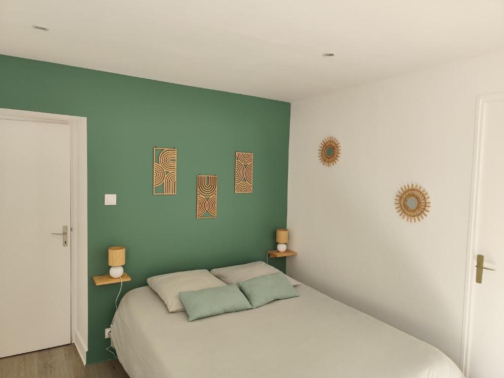 a bedroom with a white bed and a green wall at A deux pas d'la mer in Grandcamp-Maisy