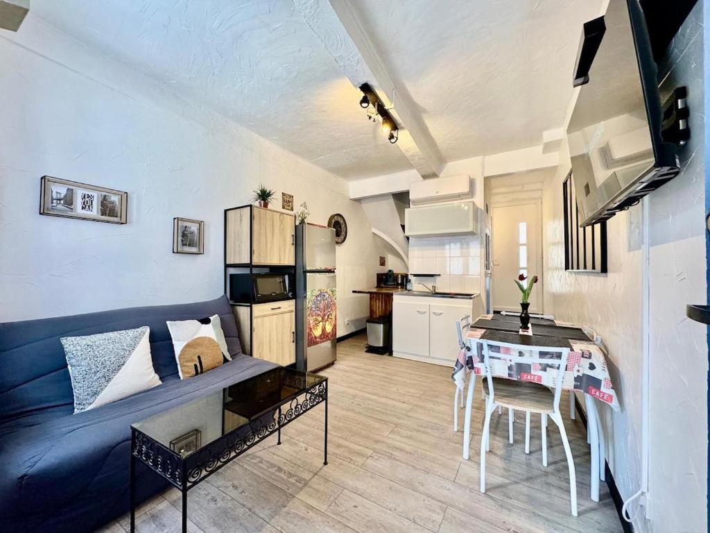 Una sala de estar con una mesa y una cocina. en Ostalet Blau Climatisé, en Béziers
