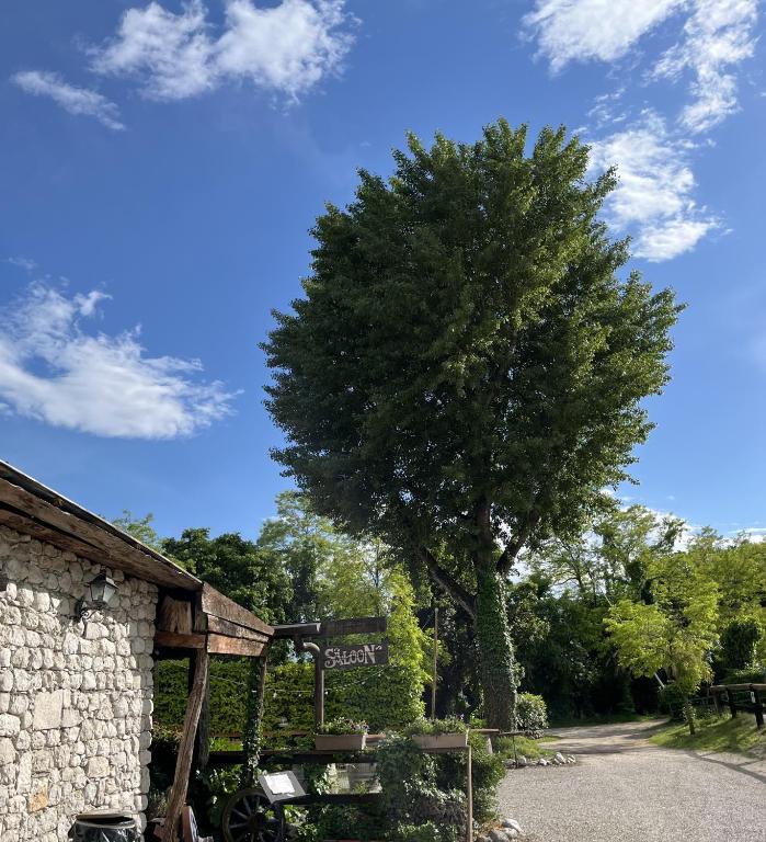 a tree sitting next to a building with a sign at Agriturismo al Ranch in Castello dʼAviano