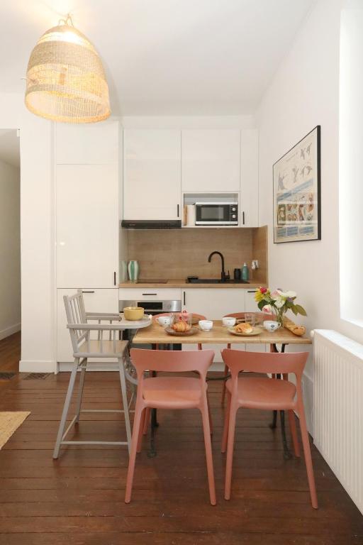 une cuisine avec une table et des chaises et une cuisine avec des armoires blanches dans l'établissement Chalet Aux Oiseaux - by La Boite en Plus, à Chantilly