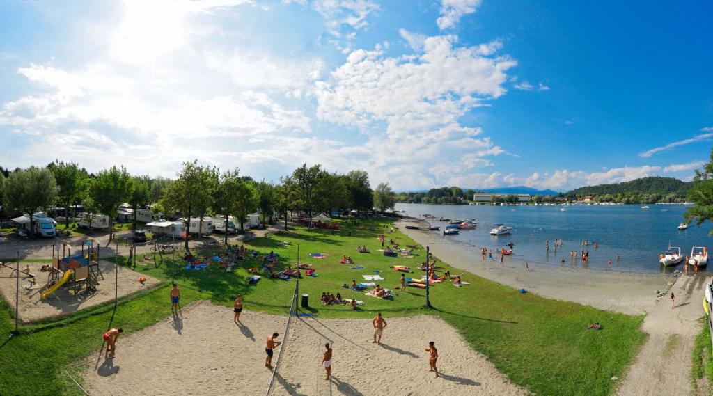 un grupo de personas en una playa cerca de un cuerpo de agua en Camping Lido Verbano, en Castelletto sopra Ticino