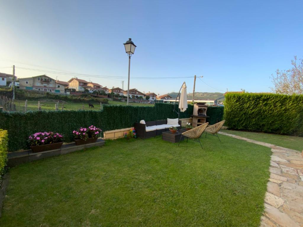 a backyard with a lawn with a couch and a umbrella at UEFA Bilbao-Castro Urdiales home in Lusa