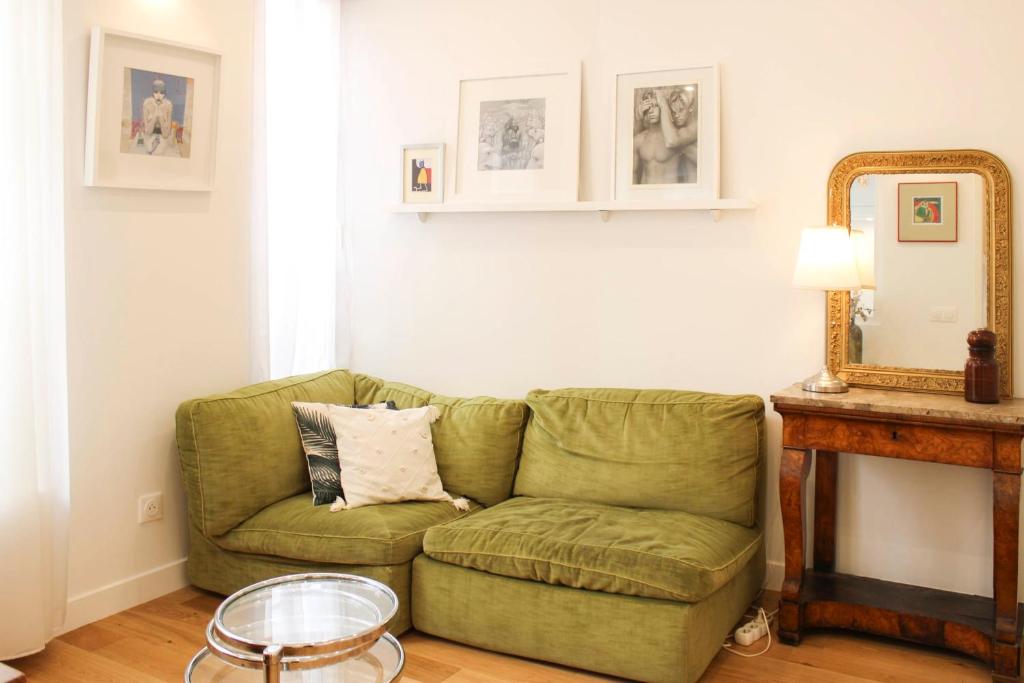 - un canapé vert dans le salon avec un miroir dans l'établissement Cozy apartment for 2 in the 11th, à Paris