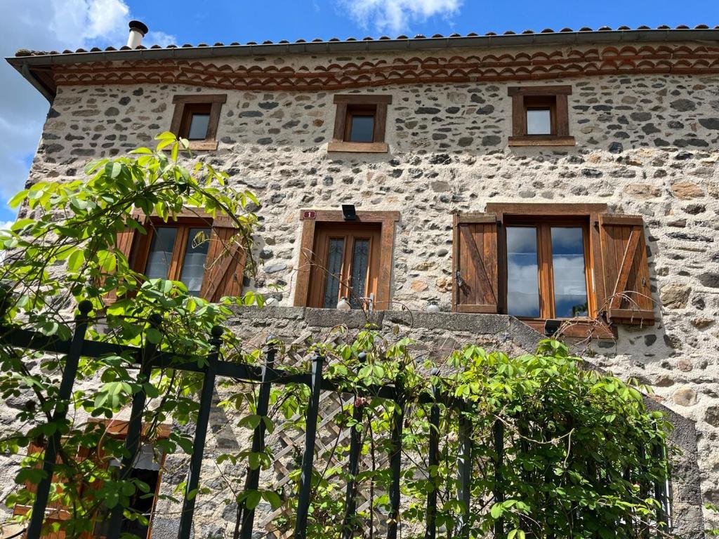 a stone house with windows and a fence at Au rythme de Plume et Louna in Molompize