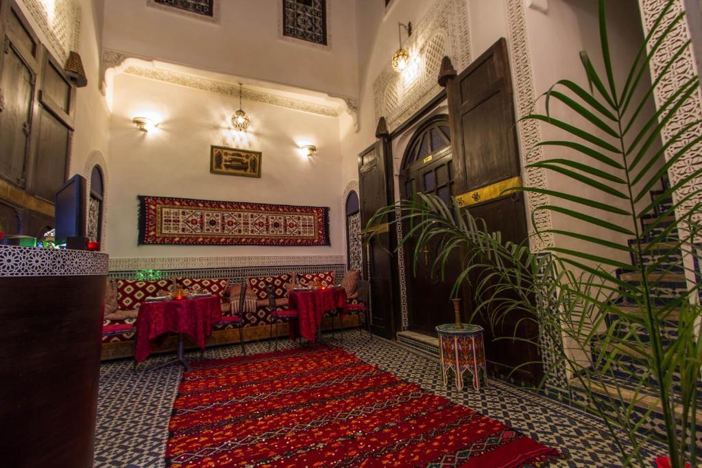 Cette chambre dispose d'un tapis rouge, d'une table et de chaises. dans l'établissement Riad Taha, à Fès