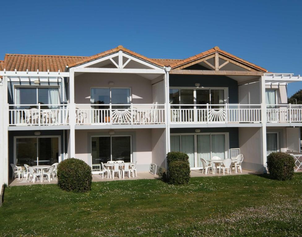 une grande maison avec des tables et des chaises sur une pelouse dans l'établissement Les Sables-d'Olonne - Terrasse, Wifi Fibre & Piscine, à 200 m de la Mer - D012, à Les Sables-dʼOlonne
