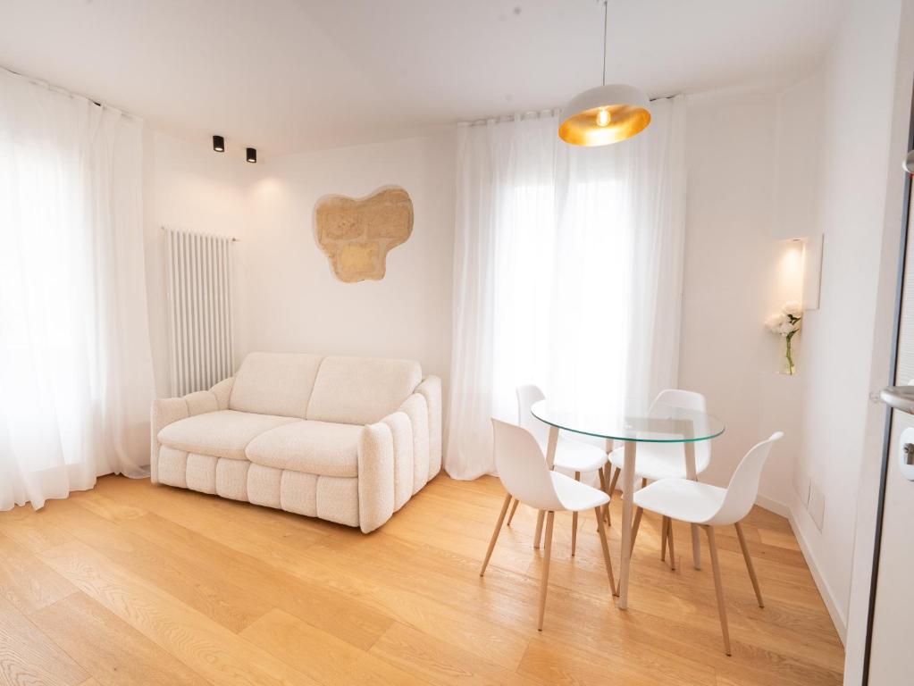 a living room with a white couch and a glass table at Maison Odile in Cefalù