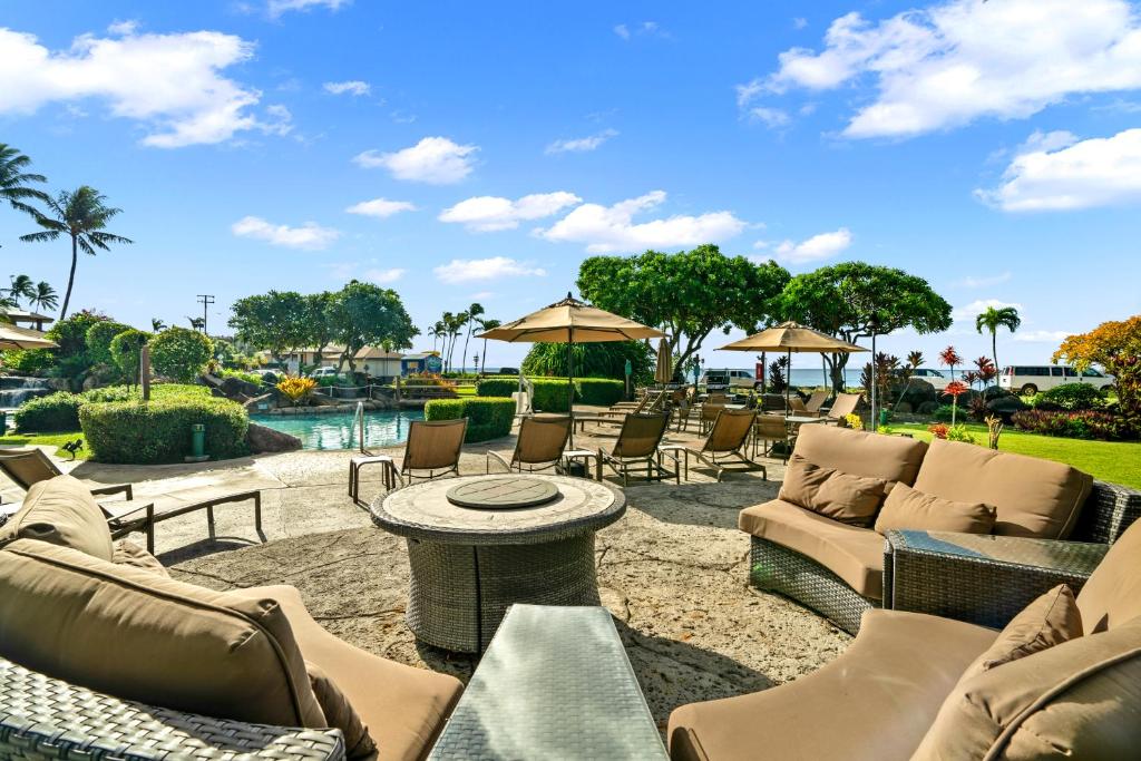 a patio with chairs and tables and a pool at Kauai Lawai Beach Resort C103 by Coldwell Banker Island Vacations in Koloa