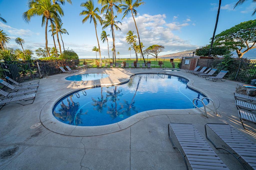 ein Swimmingpool mit Stühlen und Palmen in der Unterkunft Kauhale Makai 203 by Coldwell Banker Island Vacations in Kihei