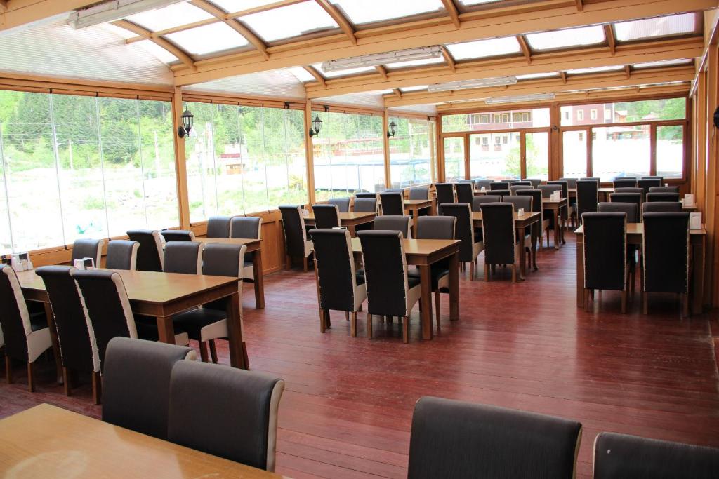 een eetkamer met tafels en stoelen en ramen bij Akpinar Hotel in Uzungol