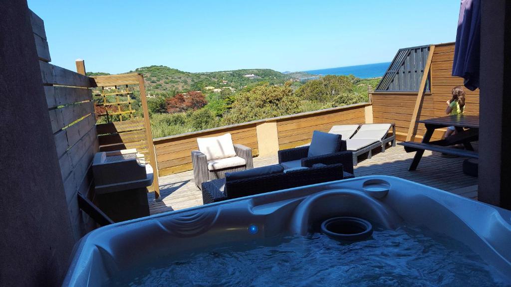 a hot tub on a balcony with a table and chairs at Appartement Cemiliana in Bonifacio