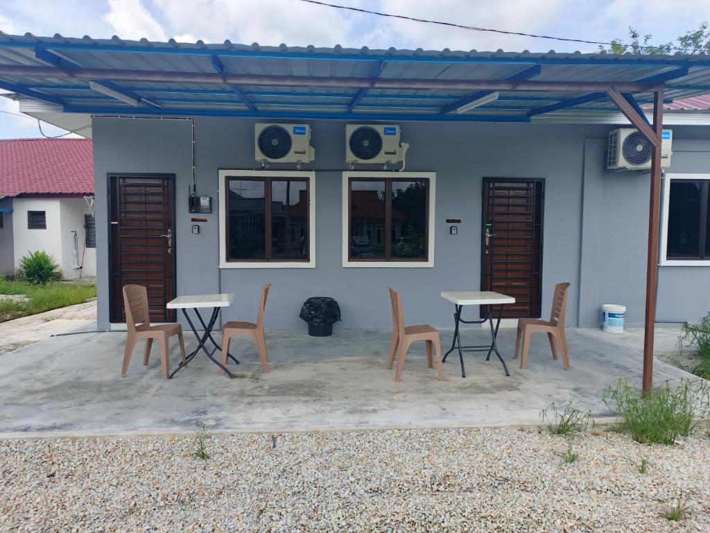 a patio with tables and chairs in front of a house at Roomstay Floral in Sri Gading