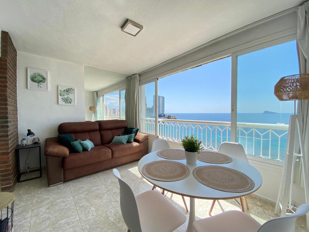 ein Wohnzimmer mit einer Couch und einem Tisch und Stühlen in der Unterkunft Torre principado 10 in Benidorm