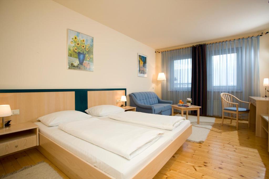 ein Schlafzimmer mit einem großen weißen Bett und einem blauen Stuhl in der Unterkunft Landgasthof Zum Alten Weinstock in Rudersdorf
