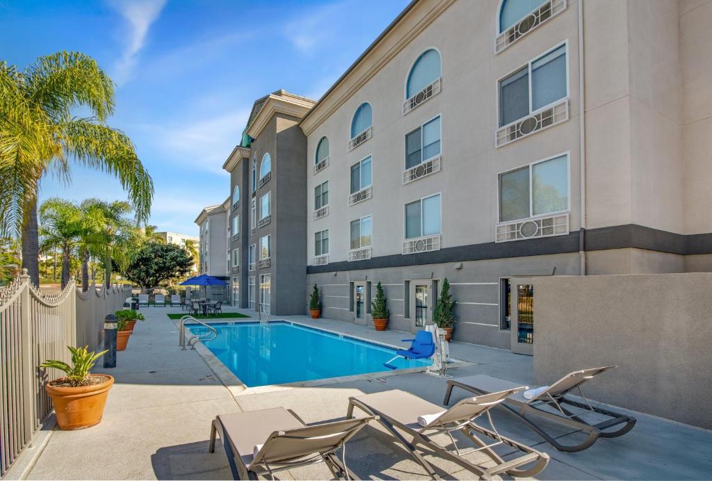 a building with a swimming pool and lounge chairs at Holiday Inn Express San Diego - Sorrento Valley by IHG in Sorrento