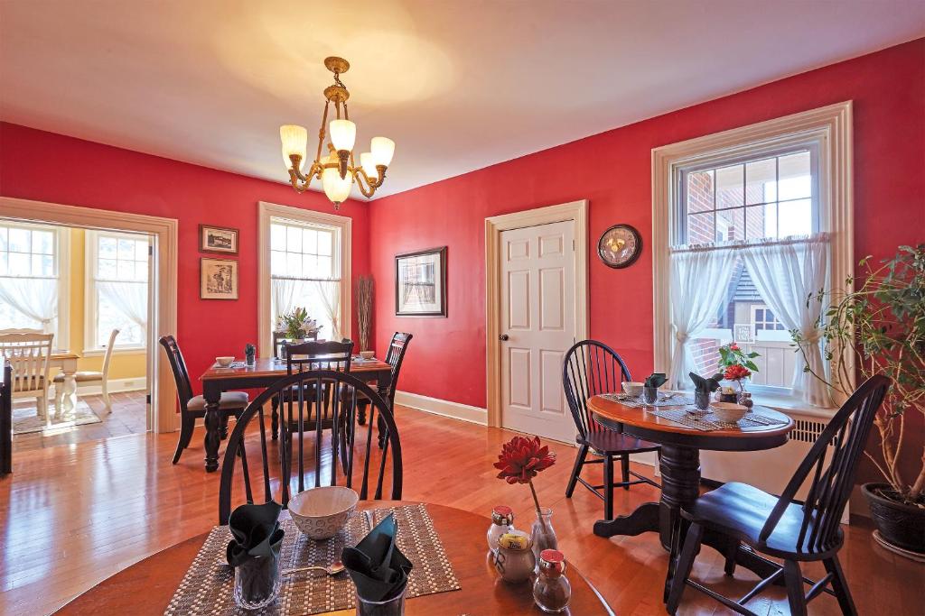 a dining room with red walls and tables and chairs at The Inn on Bay in Gravenhurst