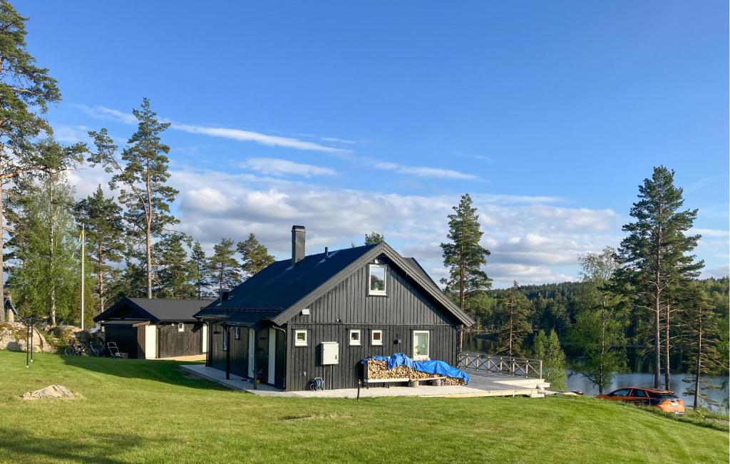 奥尔延Amazing Home In Årjäng With Lake View的草地上一栋黑色、蓝色屋顶的房子