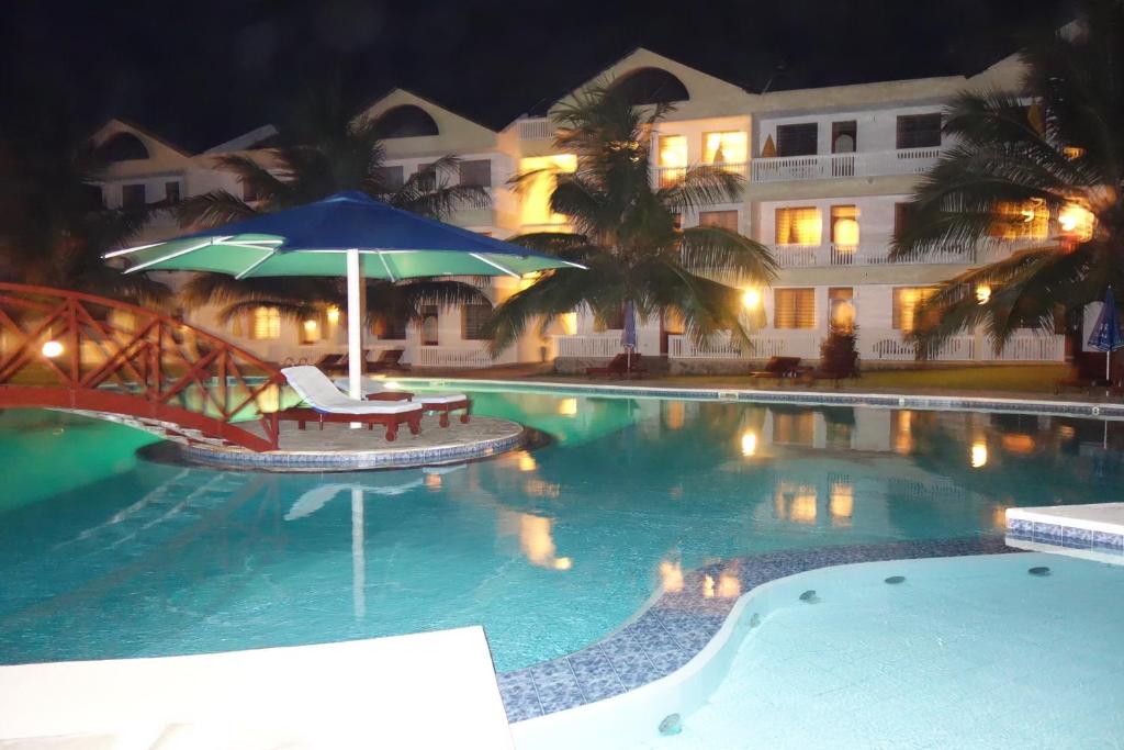 een zwembad met een tafel en een parasol bij Morning Star Diani in Diani Beach